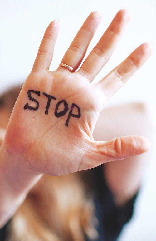 Woman shows palm with the inscription on the palm “Stop”